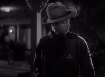 Movie still from “Destry Rides Again” (1939), directed by George Marshall – A black and white photo of a man wearing a hat; Medium shot, Over the shoulder angle