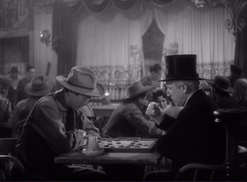 Movie still from “Destry Rides Again” (1939), directed by George Marshall – Two men are playing a game of checkers in a restaurant; Medium shot, High angle