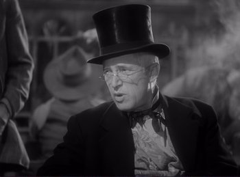 Movie still from “Destry Rides Again” (1939), directed by George Marshall – An older man wearing a top hat and a bow tie; Close Up shot, Over the shoulder angle
