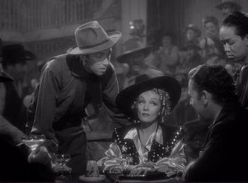 Movie still from “Destry Rides Again” (1939), directed by George Marshall – A man and a woman sitting at a dinner table; Medium shot, Over the shoulder angle