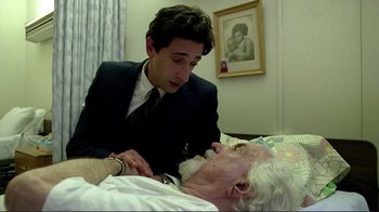 Movie still from “Detachment” (2011), directed by Tony Kaye – An older man laying in a bed with a younger man; Medium shot, Over the shoulder angle