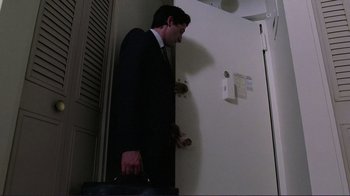 Movie still from “Detachment” (2011), directed by Tony Kaye – A man in a suit and tie standing in front of a door; Medium shot, Low angle