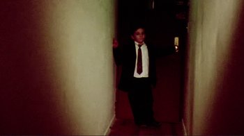 Movie still from “Detachment” (2011), directed by Tony Kaye – A boy in a suit and tie standing in a hallway; Wide shot, High angle