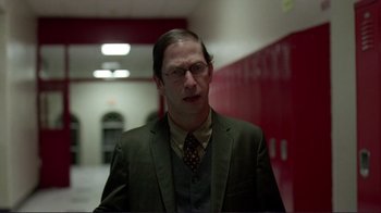 Movie still from “Detachment” (2011), directed by Tony Kaye – A man in a suit and tie standing in front of a hallway; Medium shot, Over the shoulder angle