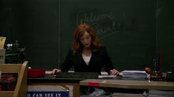 Movie still from “Detachment” (2011), directed by Tony Kaye – A woman sitting at a desk in front of a chalkboard; Wide shot, High angle