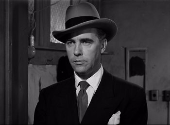 Movie still from “Detective Story” (1951), directed by William Wyler – A black and white photo of a man in a suit and hat; Close Up shot, Low angle