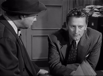 Movie still from “Detective Story” (1951), directed by William Wyler – A man in a suit and tie talking to another man in a suit and tie; Medium shot, Over the shoulder angle