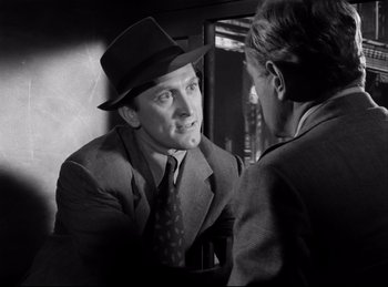 Movie still from “Detective Story” (1951), directed by William Wyler – A man wearing a suit and hat talking to a woman; Close Up shot, Over the shoulder angle