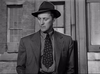 Movie still from “Detective Story” (1951), directed by William Wyler – A black and white photo of a man in a suit and tie; Medium shot, Low angle