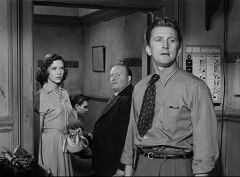 Movie still from “Detective Story” (1951), directed by William Wyler – A group of people standing next to each other in a room; Medium shot, Low angle
