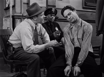 Movie still from “Detective Story” (1951), directed by William Wyler – A group of men sitting on a bench talking to each other; Medium shot, Low angle