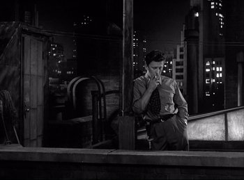 Movie still from “Detective Story” (1951), directed by William Wyler – A black and white photo of a man smoking a cigarette; Medium shot, Low angle