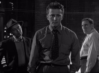 Movie still from “Detective Story” (1951), directed by William Wyler – A group of men standing next to each other in front of a brick wall; Medium shot, Low angle