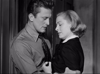 Movie still from “Detective Story” (1951), directed by William Wyler – A man and a woman holding each other in front of a wall; Medium shot, Low angle