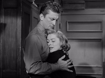 Movie still from “Detective Story” (1951), directed by William Wyler – A man and a woman embracing each other in front of a door; Medium shot, Low angle