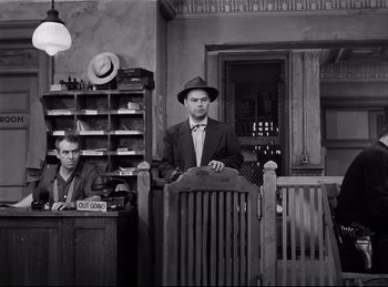 Movie still from “Detective Story” (1951), directed by William Wyler – A man in a suit and hat standing next to a man in a suit; Wide shot, Low angle