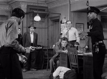 Movie still from “Detective Story” (1951), directed by William Wyler – A black and white photo of a group of people; Medium shot, Over the shoulder angle