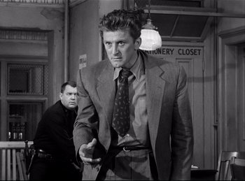 Movie still from “Detective Story” (1951), directed by William Wyler – A black and white photo of a man in a suit and tie; Medium shot, Low angle