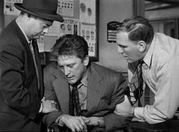 Movie still from “Detective Story” (1951), directed by William Wyler – A group of men sitting around each other in a room; Medium shot, Low angle