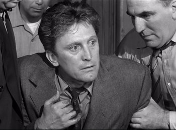 Movie still from “Detective Story” (1951), directed by William Wyler – A black and white photo of a man adjusting his tie; Close Up shot, Over the shoulder angle