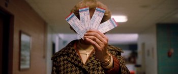 Movie still from “Detroit Rock City” (1999), directed by Adam Rifkin – A person holding a bunch of tickets in front of their face; Medium shot, High angle