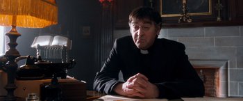 Movie still from “Detroit Rock City” (1999), directed by Adam Rifkin – A man sitting at a table with his hands crossed; Close Up shot, Low angle