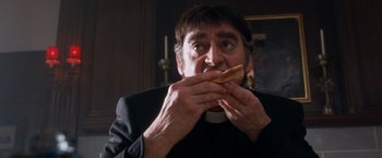 Movie still from “Detroit Rock City” (1999), directed by Adam Rifkin – A man eating a sandwich while wearing a priest's outfit; Close Up shot, Low angle