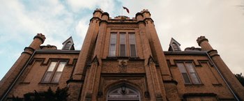 Movie still from “Detroit Rock City” (1999), directed by Adam Rifkin – A tall brick building with a flag on the top of it; Extreme Wide shot, Low angle