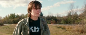 Movie still from “Detroit Rock City” (1999), directed by Adam Rifkin – A young man smoking a cigarette in a field; Close Up shot, Low angle