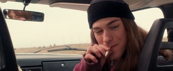 Movie still from “Detroit Rock City” (1999), directed by Adam Rifkin – A person sitting in a car while smoking a cigarette; Close Up shot, High angle