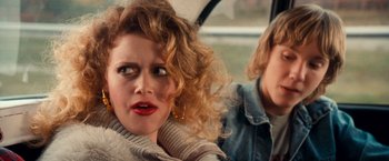 A woman with curly red hair sitting next to another woman