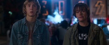 Movie still from “Detroit Rock City” (1999), directed by Adam Rifkin – Two young people standing next to each other in front of a crowd of onlookers; Medium shot, Low angle