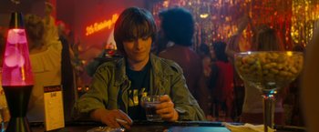 Movie still from “Detroit Rock City” (1999), directed by Adam Rifkin – A man sitting at a table with a glass of beer; Medium shot, Over the shoulder angle