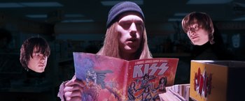 Movie still from “Detroit Rock City” (1999), directed by Adam Rifkin – A man with long hair reading a comic book; Close Up shot, Over the shoulder angle