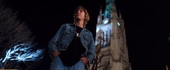 Movie still from “Detroit Rock City” (1999), directed by Adam Rifkin – A young man standing in front of a large clock tower at night; Medium shot, Low angle