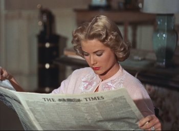 Movie still from “Dial M for Murder” (1954), directed by Alfred Hitchcock – A woman reading a newspaper while sitting in a room; Close Up shot, Low angle