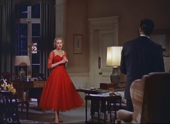 Movie still from “Dial M for Murder” (1954), directed by Alfred Hitchcock – A woman in a red dress standing in front of a man in a suit; Wide shot, Low angle