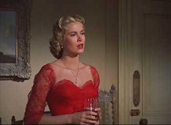 Movie still from “Dial M for Murder” (1954), directed by Alfred Hitchcock – A woman in a red dress holding a glass of wine; Medium shot, Low angle