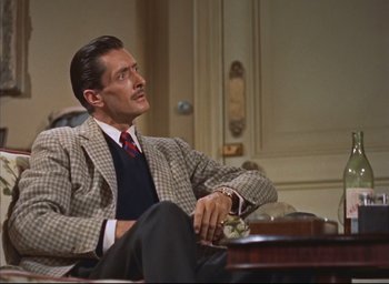 Movie still from “Dial M for Murder” (1954), directed by Alfred Hitchcock – A man sitting on a couch in a room; Medium shot, High angle