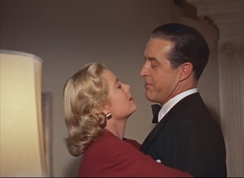 Movie still from “Dial M for Murder” (1954), directed by Alfred Hitchcock – A man and a woman in formal wear standing next to each other; Close Up shot, Low angle