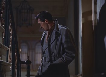 Movie still from “Dial M for Murder” (1954), directed by Alfred Hitchcock – A man in a trench coat standing next to a railing; Medium shot, Low angle