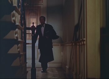 Movie still from “Dial M for Murder” (1954), directed by Alfred Hitchcock – A man in a tuxedo walking down the hall way; Wide shot, Low angle