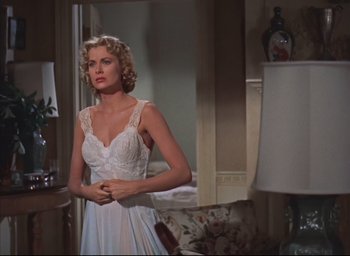 Movie still from “Dial M for Murder” (1954), directed by Alfred Hitchcock – A woman in a white dress standing in front of a mirror; Medium shot, Low angle