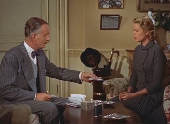 Movie still from “Dial M for Murder” (1954), directed by Alfred Hitchcock – A man and a woman sitting at a table exchanging papers; Medium shot, Low angle