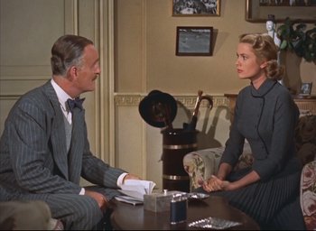 Movie still from “Dial M for Murder” (1954), directed by Alfred Hitchcock – A man and a woman sitting at a table talking to each other; Medium shot, Over the shoulder angle