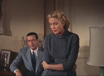 Movie still from “Dial M for Murder” (1954), directed by Alfred Hitchcock – A man and a woman standing next to each other in a room; Medium shot, Low angle