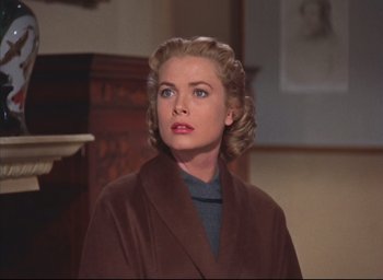 Movie still from “Dial M for Murder” (1954), directed by Alfred Hitchcock – A woman in a brown coat looking to her left; Close Up shot, Over the shoulder angle