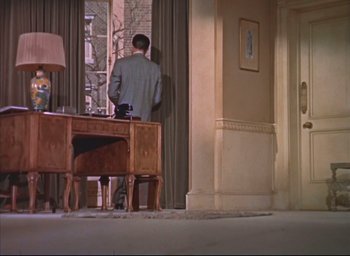 Movie still from “Dial M for Murder” (1954), directed by Alfred Hitchcock – A man standing in front of a desk looking out a window; Wide shot, Low angle