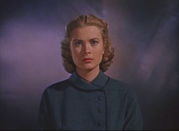Movie still from “Dial M for Murder” (1954), directed by Alfred Hitchcock – A woman in a blue jacket is looking at the camera; Close Up shot, Low angle
