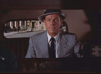 Movie still from “Dial M for Murder” (1954), directed by Alfred Hitchcock – A person wearing a suit and a hat; Medium shot, Over the shoulder angle